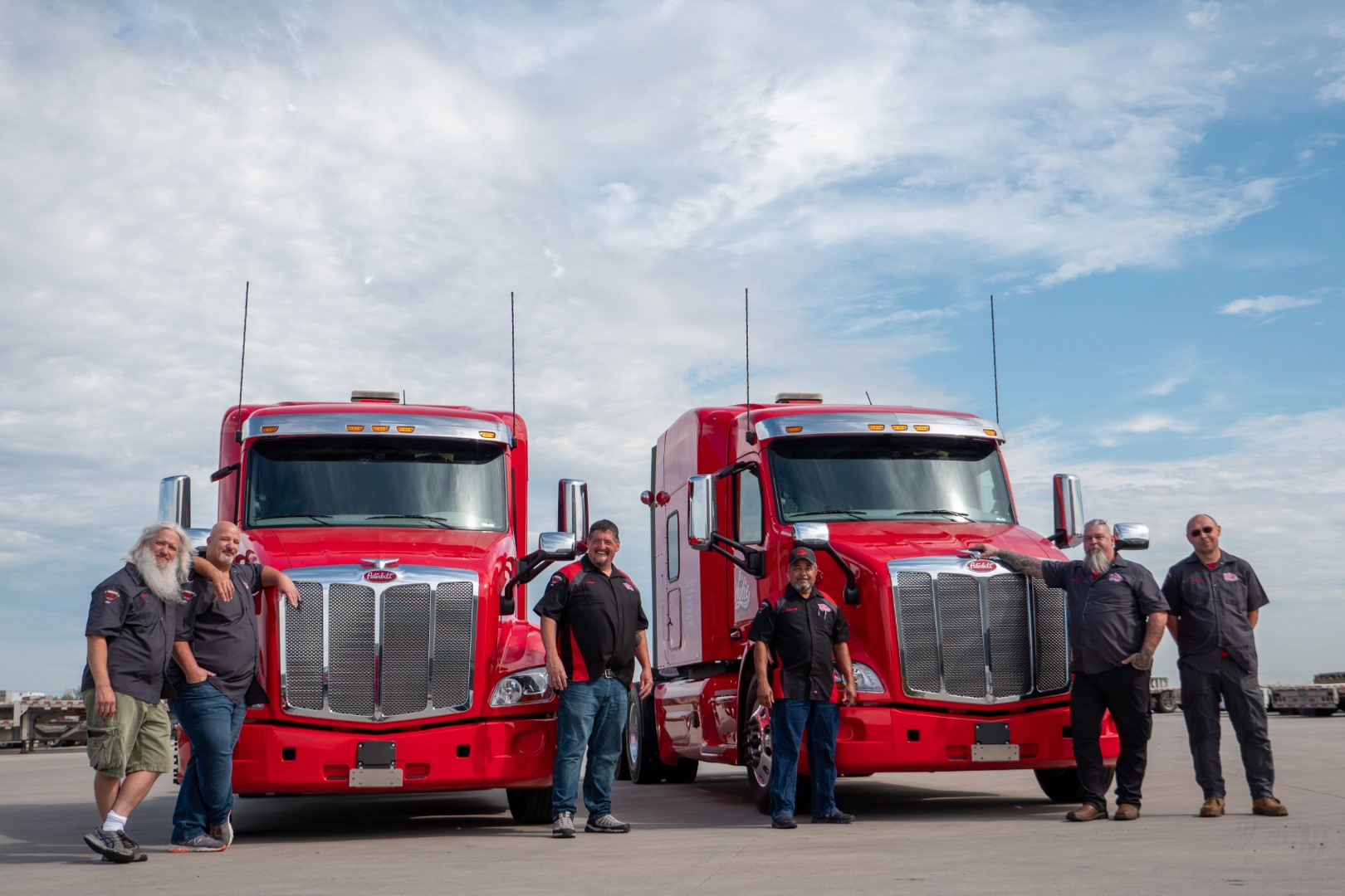 Six men standing near two trucks